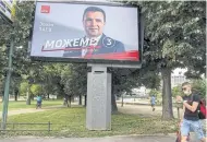  ?? AFP ?? A man walks near the electoral billboard of Zoran Zaev, leader of the ruling party SDSM in Skopje.