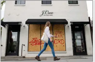  ?? (AP/Andrew Harnik) ?? A woman walks past a boarded-up J. Crew storefront in Washington last week.