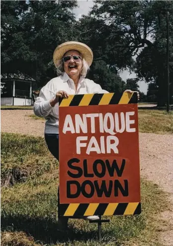  ?? Chronicle file photo ?? Emma Lee Turney plants a sign along FM 1457 at the entrance to the historic Rifle Associatio­n Hall in Round Top, in this c. 1992 photo.