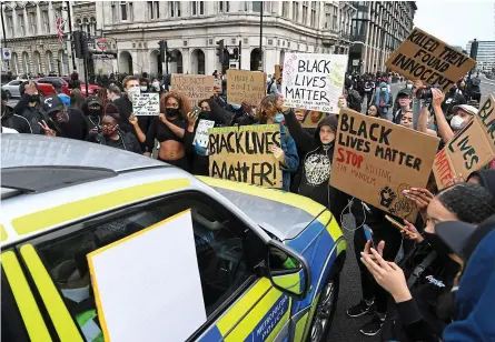  ??  ?? Hemmed in: Group of protesters waving placards gather around a police car in Parliament Square