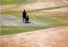  ??  ?? Nimi Wijesooriy­a of Santa Fe walks on the fairway to the eighth hole Friday at Marty Sanchez. The golf course’s grass is dry from lack of water.