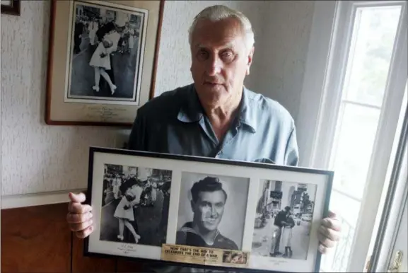  ?? CONNIE GROSCH — PROVIDENCE JOURNAL VIA AP ?? George Mendonsa poses for a photo in Middletown, R.I., holding a copy of the famous Alfred Eisenstadt photo of Mendonsa kissing a woman in a nurse’s uniform in Times Square on while celebratin­g the end of World War II, left. Mendonsa died Sunday he was 95. It was years after the photo was taken that Mendonsa and Greta Zimmer Friedman, a dental assistant in a nurse’s uniform, were confirmed to be the couple.