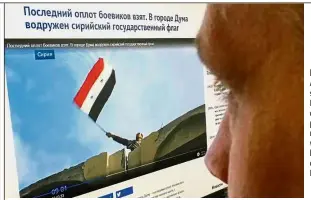  ??  ?? Recaptured:
A computer screen in Moscow displaying a web page showing a man waving what appears to be a Syrian flag over a building in Douma. — AFP