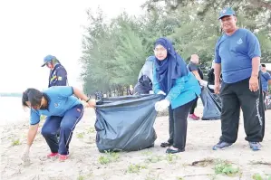  ??  ?? NORLIZA (kanan) turut sama menyertai aktiviti pembersiha­n pantai.