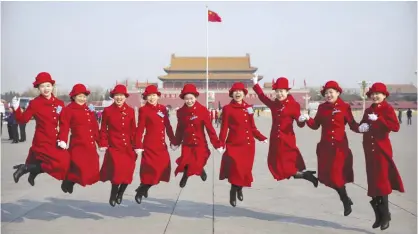  ??  ?? BEIJING: Bus ushers leap as they pose for a group photo at Tiananmen Square during a plenary session of the National People’s Congress in Beijing yesterday. China will raise its defense budget by about 7 percent this year, a government spokeswoma­n...