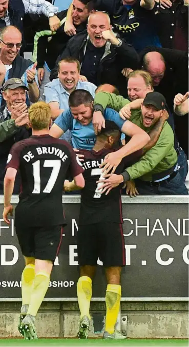  ?? — Reuters ?? Fans’ favourite: Manchester City’s Raheem Sterling is hugged by supporters after scoring the third goal in the 3-1 win over Swansea in the English Premier League match at the Liberty Stadium on Saturday.