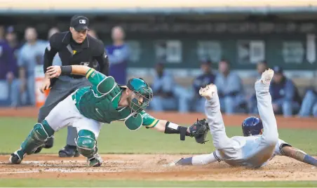 ?? Photos by Scott Strazzante / The Chronicle ?? The tag by A’s ccatcher Chris Herrmann is too late as Orlando Arcia scores on Christian Yelich’s double in the third.