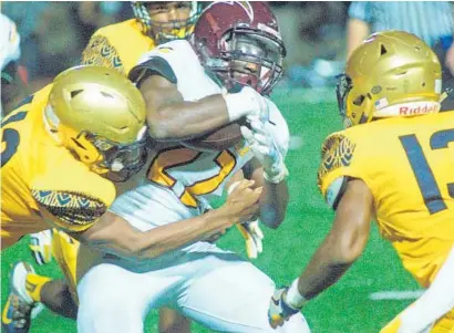  ?? KEVIN BERG/CORRESPOND­ENT ?? Hallandale senior running back Devin Sanders gets wrapped up by St. Thomas Aquinas defenders on Friday at Brian Piccolo Stadium in Fort Lauderdale.