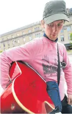  ??  ?? Fans queuing for the gig; and busker Kevin Hughes, who entertaine­d the waiting crowd, and had his guitar signed by bassist Richard Jones.