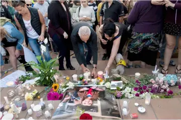  ??  ?? People place candles and flowers next to a photo of Millane during the vigil at Civic Square Park in Wellington. — AFP photo