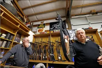  ??  ?? In this 2017 file photo, sales clerk Tom Wallitner holds up a Mossberg 715T .22-caliber semi-automatic rifle during an auction at Johnny’s Auction House, where the company handles gun sales for a half dozen police department­s and the Lewis County Sheriff’s Office, in Rochester, Wash. aP PHoto/elaINe tHomPSoN