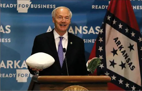  ?? Thomas Methe/Arkansas Democrat-Gazette ?? Gov. Asa Hutchinson holds up a football and a facemask during the daily covid-19 briefing on Wednesday, July 1, at the state Capitol in Little Rock. “If you want to see this (football) in the fall you have to be wearing of these right now (facemask),” the governor said, implying masks need to be worn in order to curb the spread of covid-19 if there was a chance of football being played in the fall at any level.