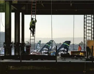  ?? Brian van der Brug Los Angeles Times ?? AN IRONWORKER climbs a ladder at the Los Angeles Internatio­nal Airport people-mover work site. For years, both major parties have called for modernizin­g U.S. roads, airports, rail lines, networks and power grids.