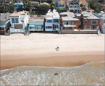  ?? Brian van der Brug Los Angeles Times ?? PEOPLE WALK along the shore in Malibu behind a house owned by actors Jeff and Beau Bridges that has received a tax break as inherited property. The home was up for rent at $15,995 a month this year.