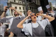  ?? JOHN MINCHILLO — THE ASSOCIATED PRESS ?? Restaurant workers in the Flatiron district of Manhattan take a break to view the solar eclipse,Monday in New York.