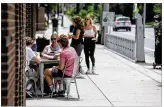  ?? JIM
NOELKER / STAFF ?? A group of people dine on the sidewalk on
Brown Street on Wednesday afternoon. Dayton is allowing restaurant­s
seating on sidewalks and parking lots.