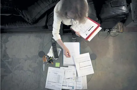  ?? Robert Bumsted, The Associated Press ?? Bonney Ginett sifts through paperwork for her applicatio­n to a federally-funded program to help pay back rent March 18 in the Queens borough of New York.