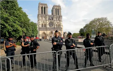  ?? AP ?? Police officers stand behind the security barriers in front of Notre Dame Cathedral as France paid a day-long tribute yesterday to the Paris firefighte­rs who saved cathedral from collapse.