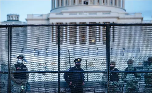  ?? Photo: AFP ?? A Capitol police officer stands with members of the National Guard behind a crowd control fence surroundin­g Capitol Hill a day after a pro-Trump mob broke into the US Capitol on Thursday in Washington, DC.