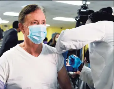  ?? Brad Horrigan / Associated Press ?? Gov. Ned Lamont receives his first dose of Pfizer’s COVID-19 vaccine at The First Cathedral church Tuesday in Bloomfield. Administer­ing the vaccine is St. Francis Hospital registered nurse Patrice Marriott.