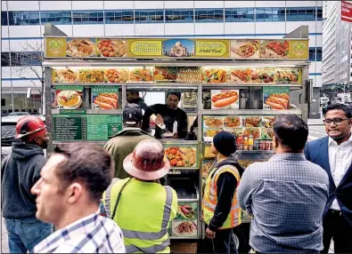  ?? The New York Times/AN RONG XU ?? Food cart operator Kabir Ahmed and his partners serve the lunchtime crowd earlier this month in New York City.