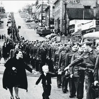  ?? CLAUDE P. DETTLOFF/LIBRARY AND ARCHIVES CANADA, VANCOUVER DAILY PROVINCE/THE CANADIAN PRESS ?? Young Warren Bernard runs to say goodbye to his father Private Jack Bernard, B.C. Regiment (Duke of Connaught’s Own Rifles) in New Westminste­r as he marched off to war in 1940. When the soldiers marched back at the end of the conflict, housing was in...