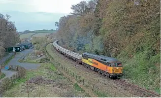  ?? RUSSELL AYRE ?? Colas Railfreigh­t Class 56 No.56302 Peco climbs past the site of the former military sidings at Tors Road Bridge, Okehampton, with the 6F27 14.36 Westbury to Crediton on April 18; one of two trains delivering 5,000 new concrete sleepers for the Okehampton line relaying in connection with the reopening the line to passengers. The Class 56 is due to remain on the line to act as a ‘Super Shunter’ for the track relaying work.