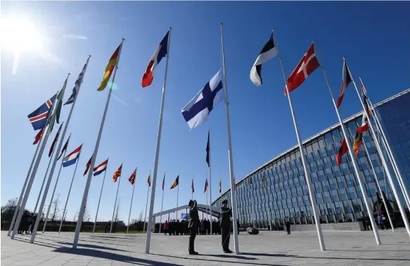  ?? AFP ?? Finnish military personnel salute as their flag is raised at Nato headquarte­rs in Brussels and the alliance expands to 31 members