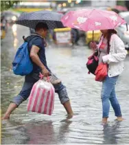  ??  ?? People cross a flooded street in Manila yesterday, as the tropical depression, made landfall in northern Luzon island.
