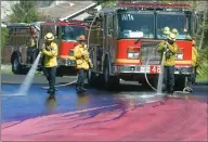  ?? Dan Watson/The Signal ?? Firefighte­rs spray water on the street on Arches Lane on Saturday to wash away fire retardant that was dropped during the Tick Fire on Thursday.