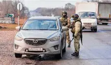  ?? Associated Press ?? Servicemen stop a car to check documents on the highway Wednesday outside Russian-controlled Luhansk, Ukraine.