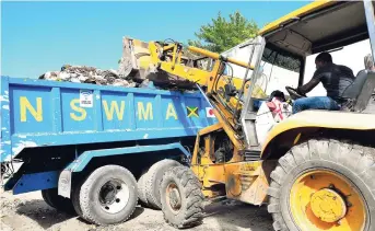  ?? NORMAN GRINDLEY/CHIEF PHOTO EDITOR ?? National Solid Waste Management Authority contractor­s remove garbage that covered a section of Drummond Street in Hannah Town in Kingston on Thursday.