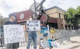  ?? STEPHEN MATUREN/GETTY ?? Protesters share their outrage as work crews put up barricades outside a police station Wednesday in Minneapoli­s.