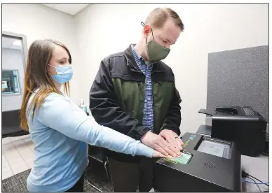  ?? (NWA Democrat-Gazette/David Gottschalk) ?? Lt. Randy Wood with Bentonvill­e’s Police Department fingerprin­ts Tiffany Steal, records supervisor, while demonstrat­ing Tuesday the fingerprin­ting device at the Police Department that is no longer supported by the previous provider. The City Council approved buying two fingerprin­ting computers Tuesday night. Go to nwaonline.com/210331Dail­y/ and nwadg.com/photos for a photo gallery.