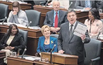  ?? CHRIS YOUNG THE CANADIAN PRESS ?? Finance Minister Charles Sousa tables the provincial budget Tuesday while Premier Kathleen Wynne looks on.