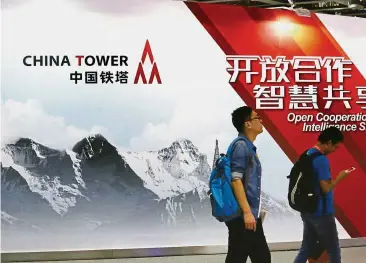  ?? — Reuters ?? Valued asset: People walk past a sign of China Tower Corp at an expo in Beijing. While the world’s largest telecom tower service provider didn’t give a fund-raising target or proposed timing of the sale in its filing dated Monday, the IPO may raise...