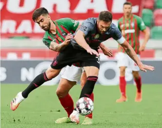  ?? — AFP ?? Halted: Maritimo’s Rodrigo Pinho (left) challenges Benfica’s Jardel during the Portuguese football match at the Maritimo stadium on Monday.