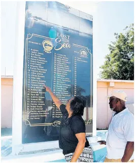  ??  ?? Estella Ebanks, president of the Greater Treasure Beach Citizens’ Alert Group, and treasurer Hursley ‘Uncle Bowl’ Moxam look at the names of their relatives on the monument erected in honour of the 62 fishermen lost at sea over the years.