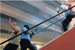  ?? REUTERS ?? A police officer, centre, secures an elevator as frightened foreigners flee inside Westgate Shopping Centre in Nairobi on Saturday.