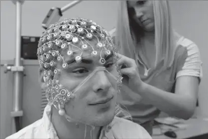  ??  ?? In this May 31 photo, research assistant Sara Mason places an EEG net for detecting brain activity on fellow assistant Kevin Real at the University of Nebraska’s Center for Brain, Biology and Behavior in Lincoln, Neb.