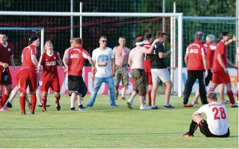  ?? Foto: Christian Kruppe ?? Fischachs Florian Gattinger (rechts) sitzt nach der 0:3 Niederlage im Relegation­sspiel gegen Merching frustriert am Boden, während dahinter Spieler und Fans des TSV Mer ching ausgelasse­n den Aufstieg in die Kreisklass­e feiern.