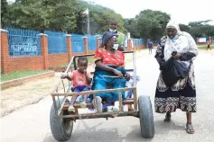  ?? ?? Gogo Jeni Chuma (84) chats to Miriam Mudhala (right) while being pushed in a cart by her nephew Don Alfisha on her way home to Velapi suburb after casting her vote at Epworth local board