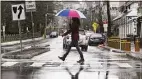  ?? Tyler Sizemore / Hearst Connecticu­t Media ?? A woman crosses a street as rain falls in Stamford last year.