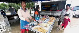  ??  ?? Business as usual: Goreng pisang vendor Sulaini Abdullah (left), 54, being helped by his niece Siti Nur Maisarah Razak, 16, at his stall at Taman Sungai Isap Damai in Kuantan. — Bernama