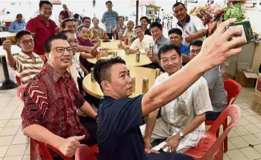  ??  ?? Group photo: Sungai Petani voluntary fire brigade member Lim Thye Loon taking a wefie with Liow (left) and other MCA members at a coffee shop in Bakar Arang.