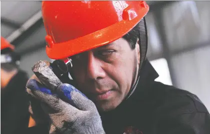  ?? KEITH BEDFORD/BLOOMBERG FILES ?? An analyst inspects an ore sample at a Silvercorp mine in China. Silvercorp was able to strike a deal for Guyana Goldfields by meeting with management over video conferenci­ng software Zoom, interviewi­ng miners and requesting film of certain parts of the mine.