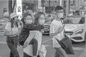  ?? GEMUNU AMARASINGH­E/AP ?? A Chinese family wearing face masks walks in a pedestrian crossing in Bangkok, Thailand on Wednesday. The coronaviru­s outbreak, centered in the Chinese city of Wuhan, has killed more than 100 people and sickened thousands.