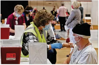  ?? BILL LACKEY/STAFF ?? Patricia Hart, a volunteer at the Clark County Combined Health District’s COVID vaccine distributi­on center, gives a Clark County resident his shot at the Upper Valley Mall.