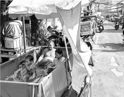  ?? AFP / Jam Sta. Rosa ?? Children and an adult cool off in a makeshift pool beside a street on a hot day in Manila on April 1, 2024.