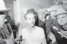  ?? ASSOCIATED PRESS ?? Lee Harvey Oswald, surrounded by detectives, talks to the media as he is led down a corridor of the Dallas police station for another round of questionin­g in connection with the assassinat­ion of President John F. Kennedy on Nov. 23, 1963.